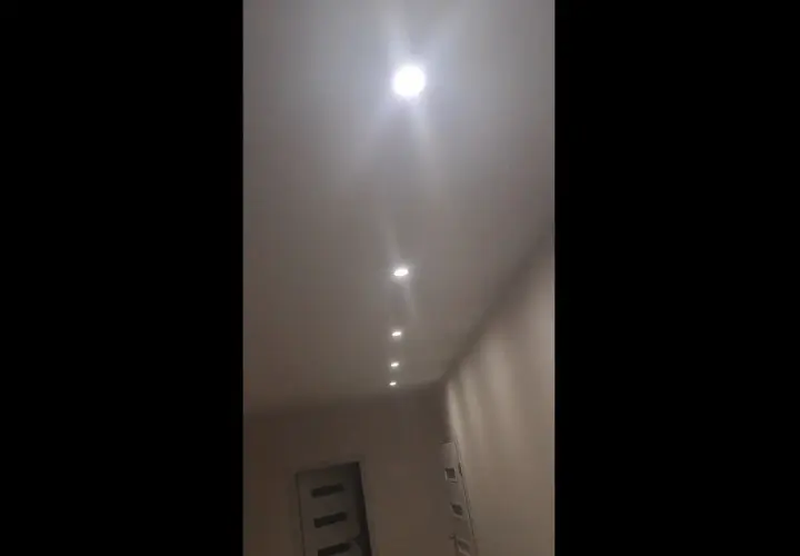 W korytarzu widać rząd wbudowanych w sufit lamp, które tworzą migające światło.