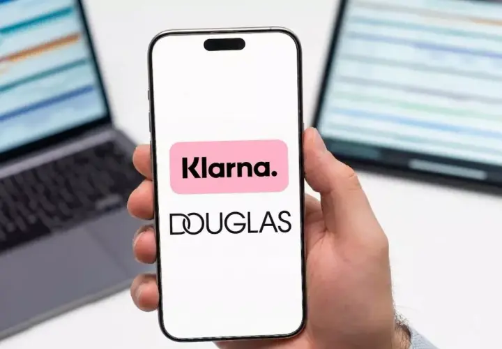 Dłoń trzyma smartfon z logo Klarna i Douglas. To ułatwia zakupy, jak douglas paypo.