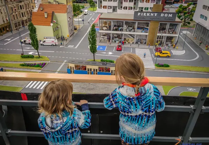Dwie dziewczynki podziwiają miniaturowe miasto, gdzie znajdują się sky tower atrakcje dla dzieci.
