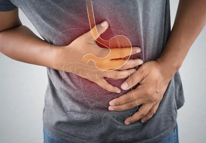 Mann hält sich den Bauch wegen eines akuten Abdomens. Die Grafik zeigt den Magen und Darm.