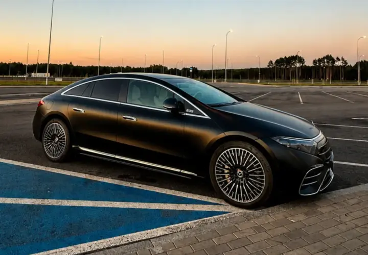 Elegancki, czarny Mercedes EQS na pustym parkingu o zachodzie słońca. Luksusowa limuzyna elektryczna prezentuje swoje aerodynamiczne linie.