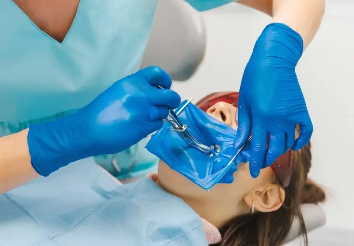 Dentysta zakłada koferdam, izolując pole zabiegowe.