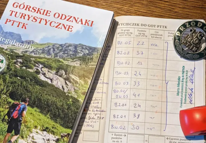 Książeczka GOT PTTK z wpisami wycieczek i odznaką przodownika.