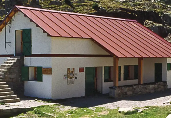 Un refugio de montaña en Cataluña, con tejado rojo y escaleras de piedra.