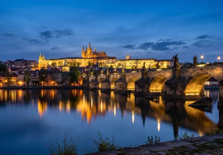 Idealny pomysł na praga na weekend: nocny widok na Most Karola i Zamek Praski, z odbiciem świateł w Wełtawie.