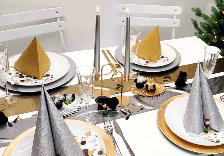 Festlich gedeckter Tisch mit Kerzen, Gläsern und Servietten in Gold und Silber. Eine tolle Silvester Idee für eine glamouröse Feier.