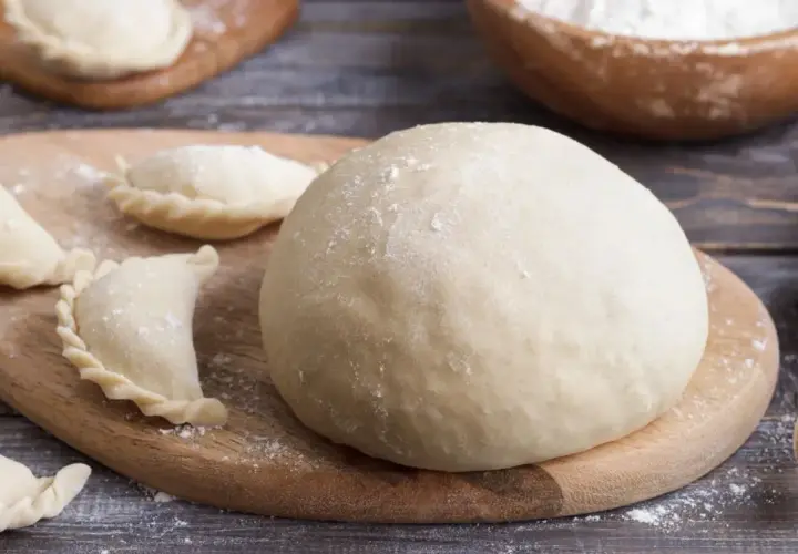 Świeże ciasto na pierogi i kilka uformowanych pierożków. Zastanawiasz się, czy ciasto na pierogi można zrobić dzień wcześniej? Tak, można!