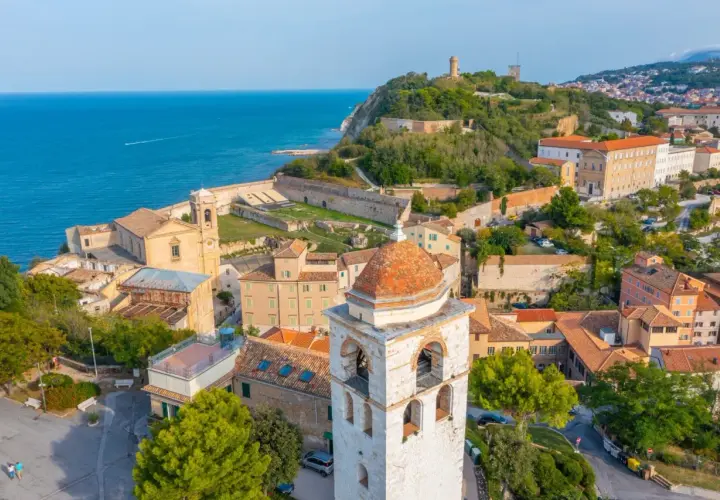 Panoramica aerea di Ancona, Marche, con il mare blu, edifici storici, un campanile e la fortezza sul colle.