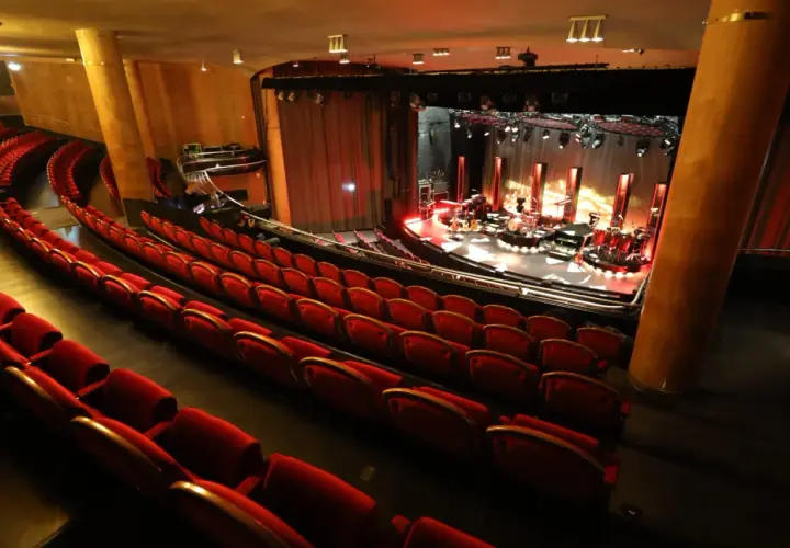 Tomma röda sammetsstolar i en teater, redo för publiken. Scenen är upplyst med instrument och redo för en konsert. En av många fina konsertlokaler i Stockholm.