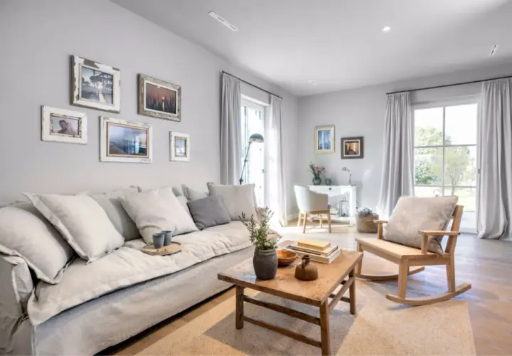 Gemütliches Wohnzimmer mit einem großen grauen Sofa, Bilderwand und Schaukelstuhl. Tolle wohnzimmer ideen graues sofa.