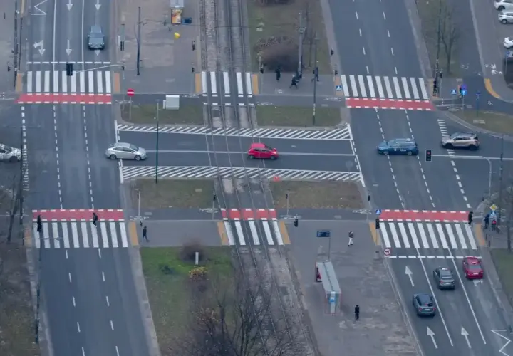 Skrzyżowanie z przejściami dla pieszych. Czerwony samochód wykonuje wyprzedzanie na pasach, ignorując pieszych.