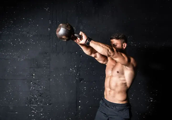 Mężczyzna ćwiczy z kettlebell. Intensywny trening, który pokazuje, co to znaczy wysiłek anaerobowy.