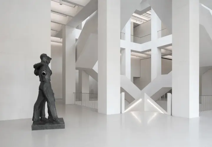 Rzeźba w nowoczesnym muzeum z betonową architekturą i schodami.
