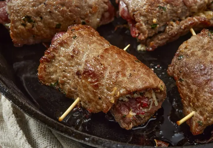 Involtini di carne succulenti, cotti in padella, con ripieno visibile e stuzzicadenti.