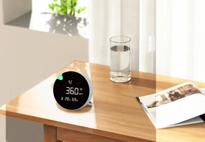 Monitor de calidad del aire muestra 360 ppm, indicando niveles de CO2 saludables en un ambiente hogareño.