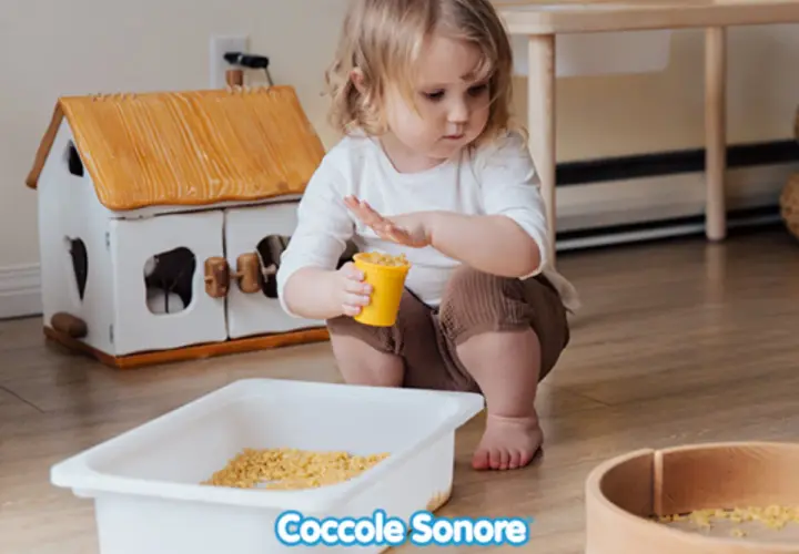 Bambina di 2 anni gioca con pasta in un vassoio, un'attività sensoriale divertente.