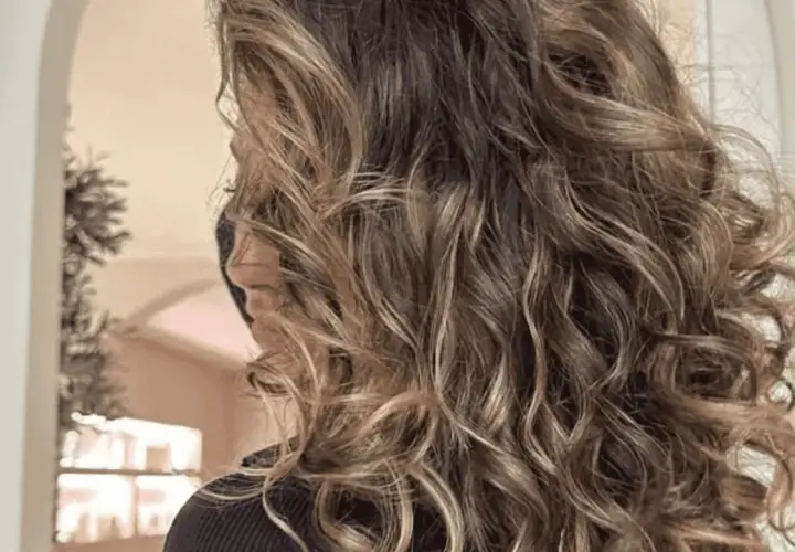Melena castaña con mechas pelo rizado, luciendo ondas naturales y un brillo espectacular.