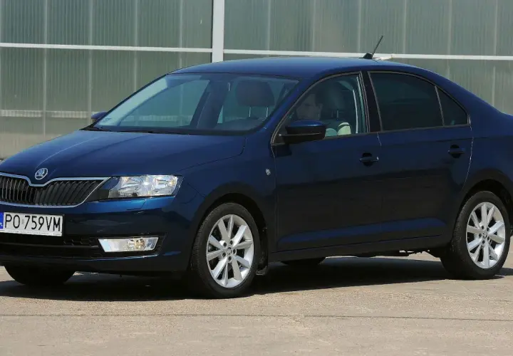 Ciemnoniebieska Skoda Rapid stoi na parkingu. Widoczny jest rozmiar opon, który idealnie pasuje do tego modelu.