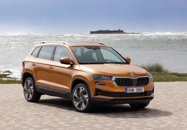 Pomarańczowa Skoda Karoq na tle morza. Sprawdź aktualny skoda cennik i wybierz swój wymarzony model.