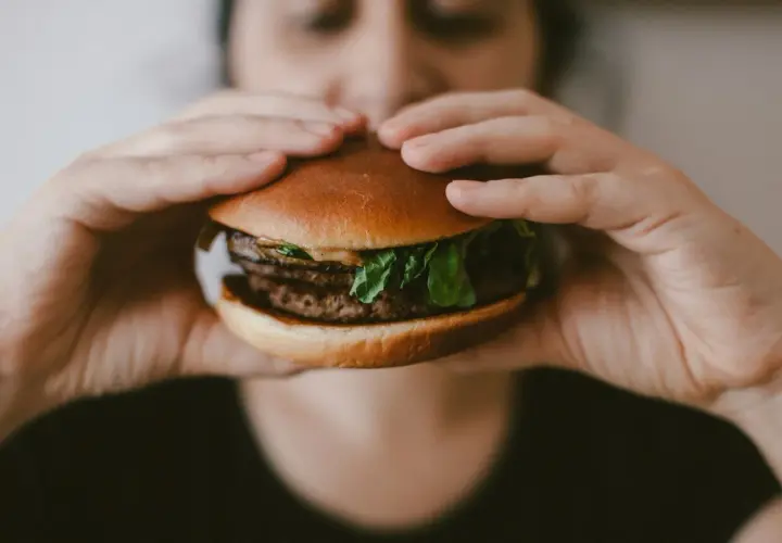 Osoba trzyma soczystego burgera, który może być wariantem McRoyal. Zastanawiasz się nad jego mcroyal kcal?
