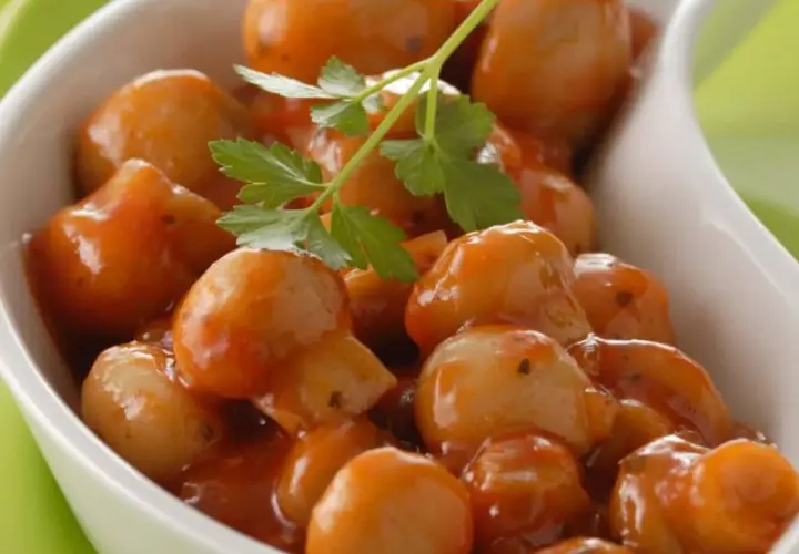 Champignons à la grecque, petits et tendres, nappés d'une sauce savoureuse et garni d'une feuille de persil.