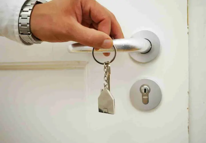 Main tenant ouvre la porte avec une clé en forme de maison. Les travaux ne sont pas finis, mais le paiement est attendu.