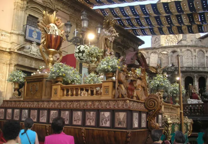 Procesión religiosa con un elaborado trono de madera adornado con flores y figuras. El **corpus 2026** se prepara para la festividad.