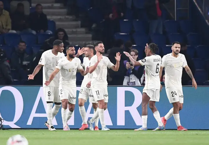 Piłkarze OGC Nice świętują bramkę przeciwko Stade de Reims. Drużyna w białych strojach z numerami 8, 2, 11, 6 i 24 cieszy się z sukcesu.