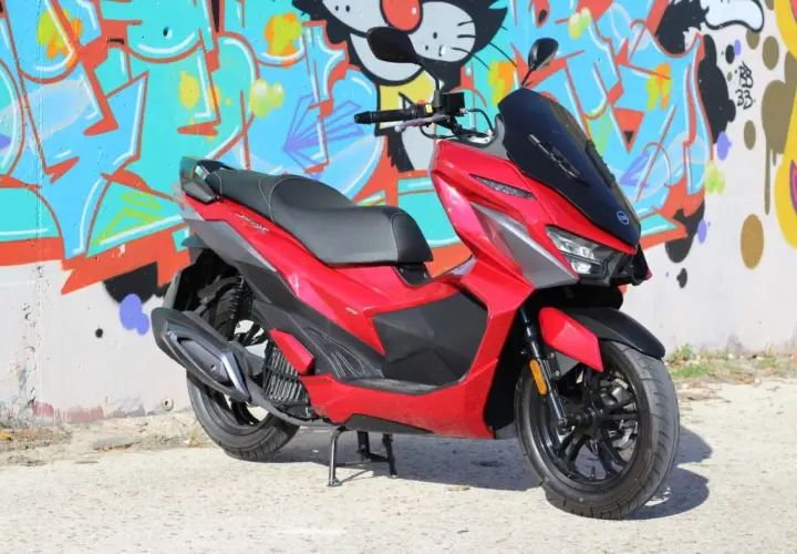 Scooter SYM Jet X 125 rojo brillante, con diseño deportivo, frente a un muro con grafitis coloridos. ¡Un estilo que inspira buenas opiniones!