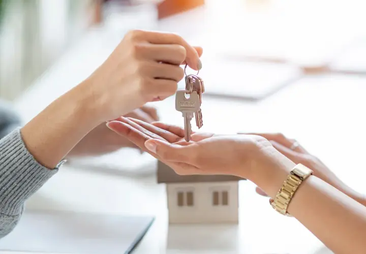 Manos intercambian llaves de una casa modelo. Un nuevo comienzo, que significa cru, se materializa en este momento.