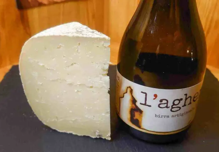 Un pezzo di formaggio stagionato accanto a una bottiglia di birra artigianale. Un abbinamento perfetto di birra e formaggio.