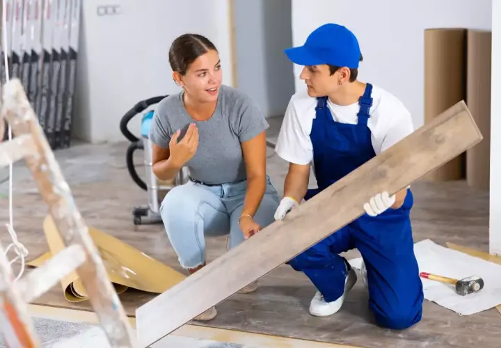 Un artisan montre une lame de parquet à une cliente. Elle s'interroge sur quels travaux peut on déduire des impôts pour ce type de rénovation.