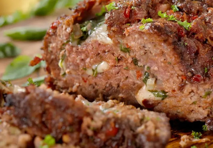 Un succulento polpettone ripieno, con formaggio filante e erbe aromatiche, pronto per essere gustato.