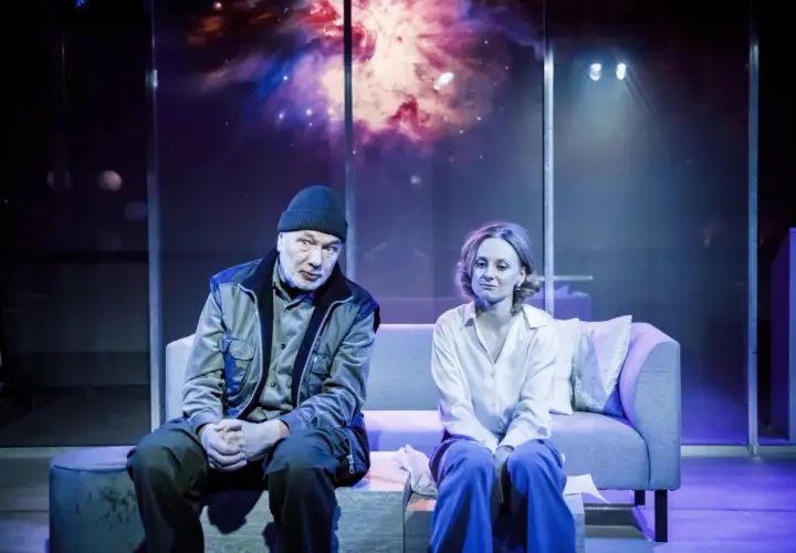 Para siedzi na kanapie w teatrze współczesnym na Mokotowie w Warszawie. Tło sceny to kosmiczna mgławica.