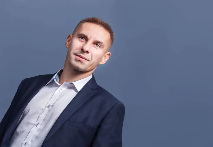 Mężczyzna w garniturze i białej koszuli, patrzący w górę.