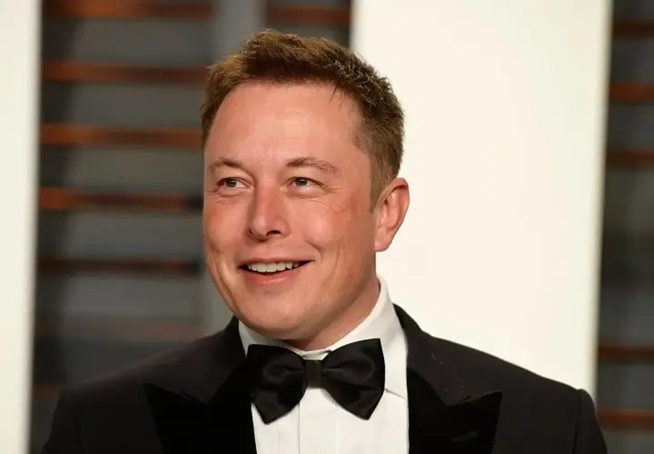 Uśmiechnięty Elon Musk w smokingu z muszką. Jego elon musk data urodzenia to 28 czerwca 1971 roku.