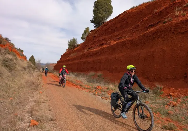 Ciclistas disfrutan de una **vía verde** con **ojos negros** en el paisaje rojizo.