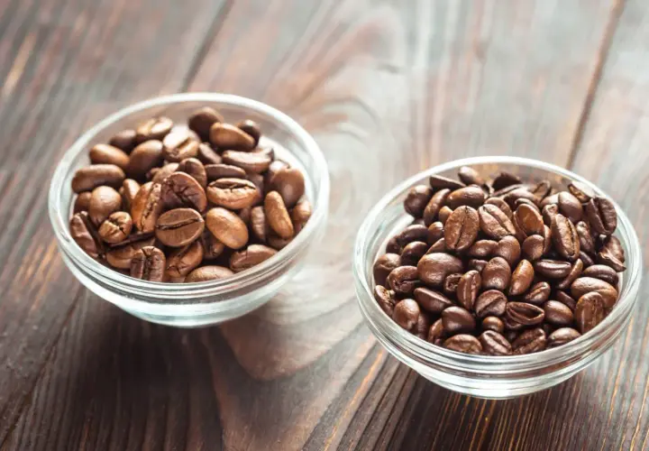 Dwie miseczki z ziarnami kawy: jedna z jaśniejszymi ziarnami arabiki, druga z ciemniejszymi, tworzącymi idealną mieszankę arabica i robusta.
