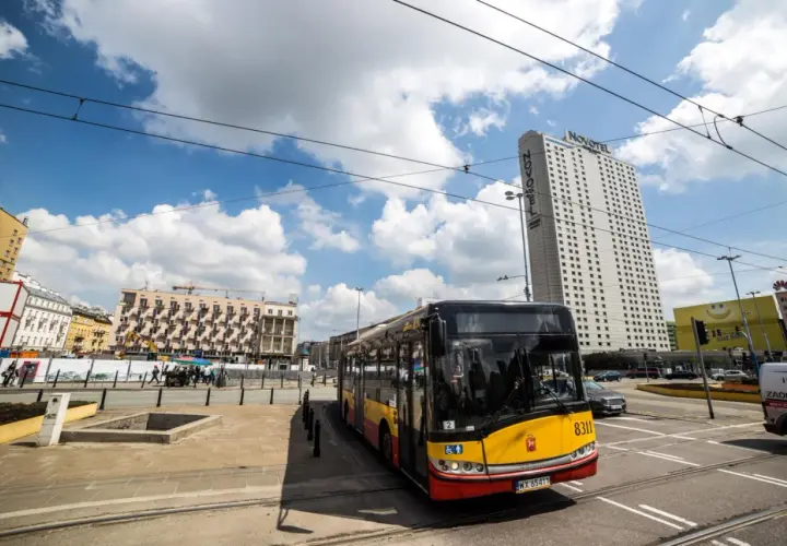 Autobus MZA Warszawa na tle wieżowca Novotel i budynków mieszkalnych.