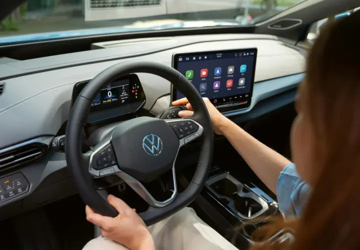 Interior de un coche eléctrico Volkswagen. Se ve el volante, la pantalla táctil central y la palanca de cambios. La dirección asistida progresiva se adapta a la velocidad.