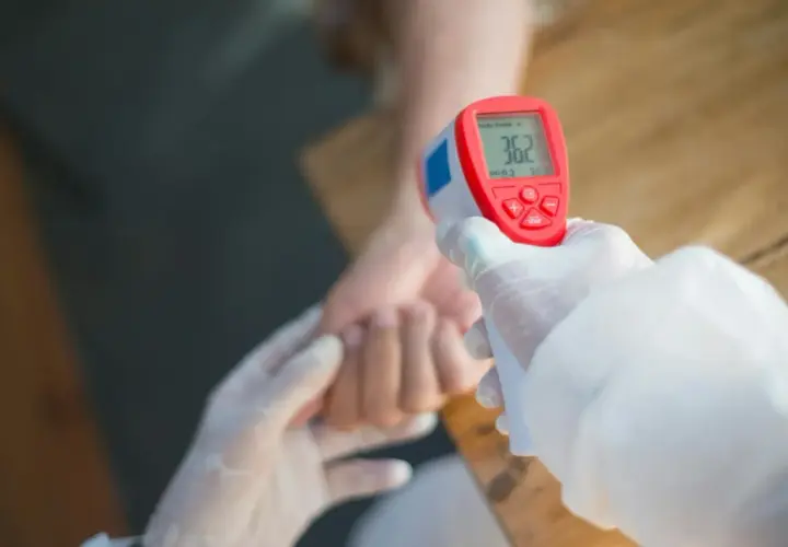 Rękawiczki i termometr bezdotykowy mierzą temperaturę, która może wskazywać na przewlekły stan podgorączkowy i zmęczenie.