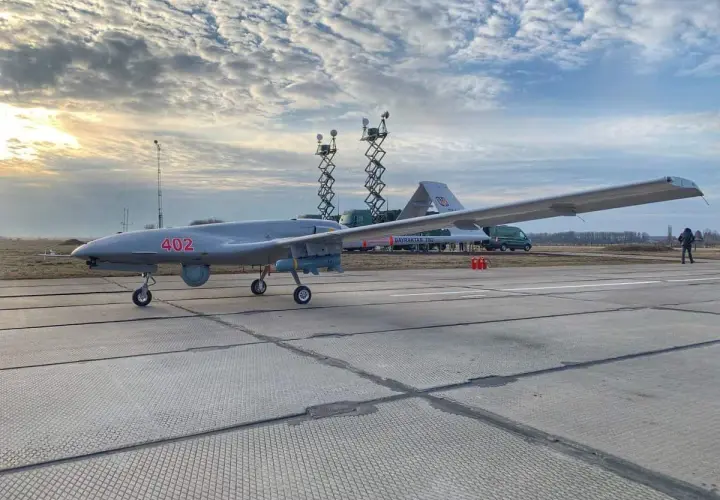 Szary dron Bayraktar TB-2 z numerem 402 na płycie lotniska, gotowy do akcji.