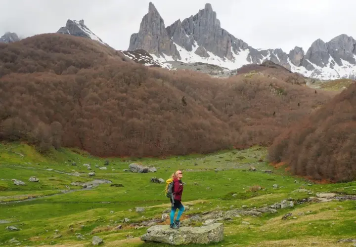 Senderista admira el majestuoso valle de Aspe, con picos nevados y bosques otoñales.