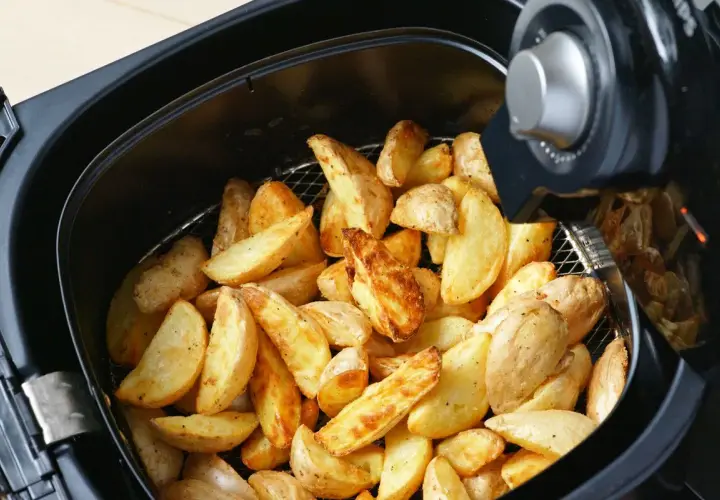 Patate a spicchi dorate e croccanti appena sfornate nella friggitrice ad aria.