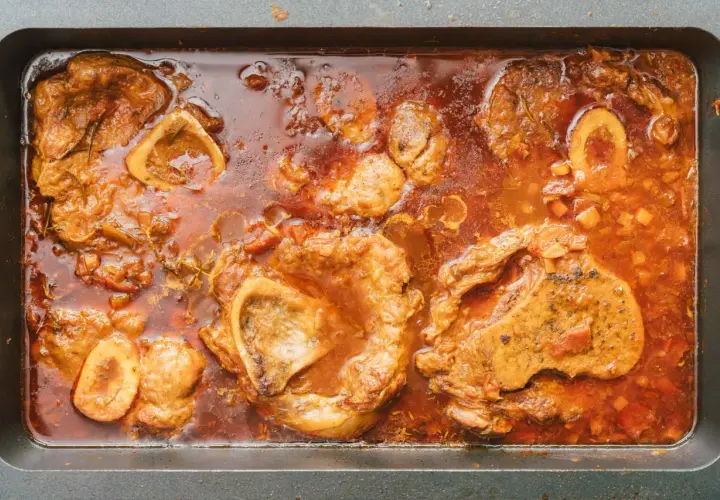 Herzhaftes Ossobuco-Rezept original italienisch: Kalbshaxenscheiben schmoren in aromatischer Sauce mit Gemüse und Kräutern in einer Bratpfanne.