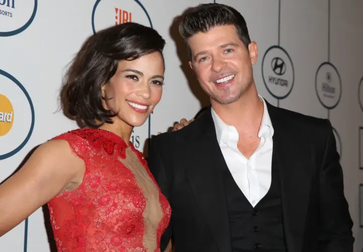 Paula Patton w czerwonej sukni i Robin Thicke na gali. Paula Patton znana z wielu filmów, uśmiecha się do aparatu.