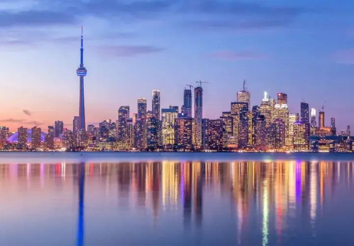 Toronto Skyline bei Dämmerung, ein Muss für jeden Besucher. Der CN Tower ragt empor, beleuchtete Wolkenkratzer spiegeln sich im Wasser.