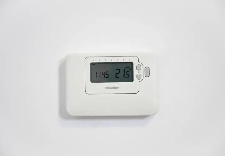 Termostato Equation en pared blanca. Muestra la hora 11:45 y la temperatura 21.5°C. Ideal para cambiar el termostato de calefacción.