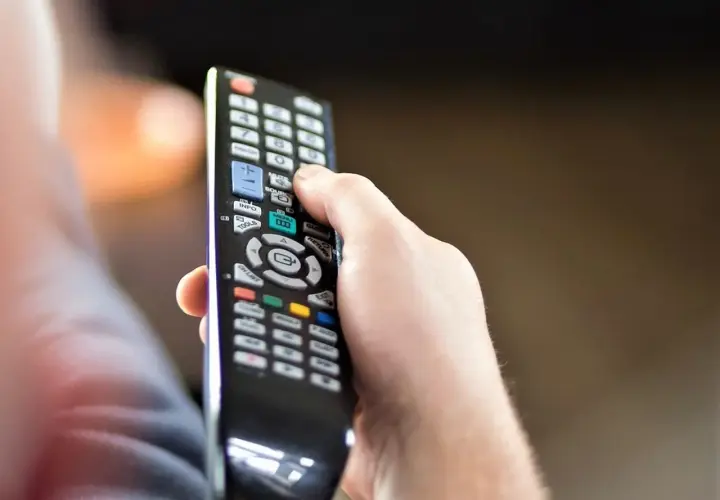 Dłoń trzyma pilot, zastanawiając się, czy telewizję naziemną można oglądać przez internet.