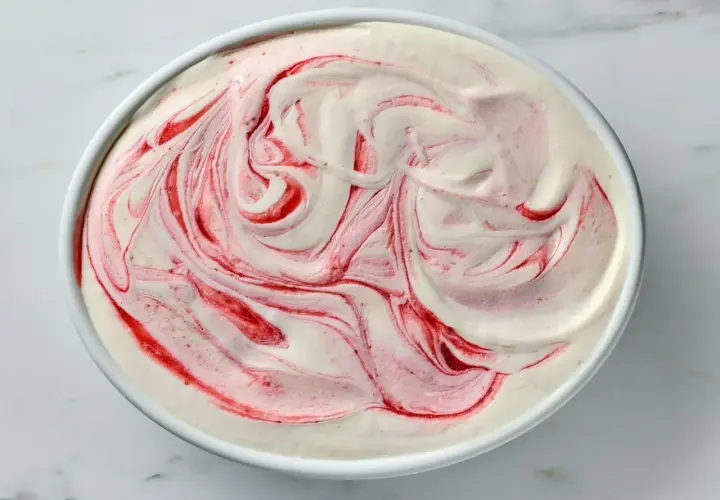 Kremowe lody jogurtowe z malinową spiralką, wyglądające jak dzieło sztuki.